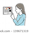 A woman checking on the intercom monitor. 139671319