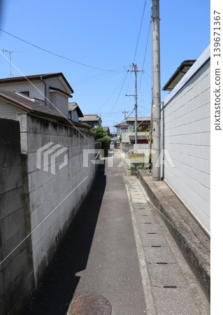 居民區的一條街道,兩側是混凝土塊牆和電線桿。 居民區的一條街道,兩側是混凝土塊牆和電線桿。 139671367