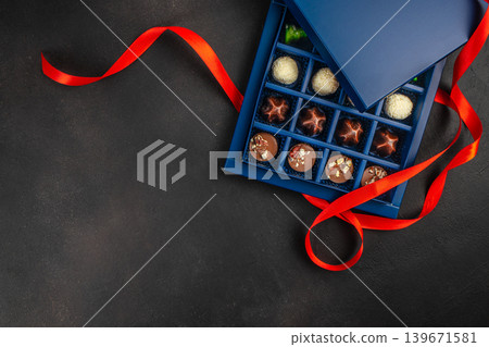 Chocolate candy box with red ribbon on dark background top view with copy space Chocolate candy box with red ribbon on dark background top view with copy space 139671581