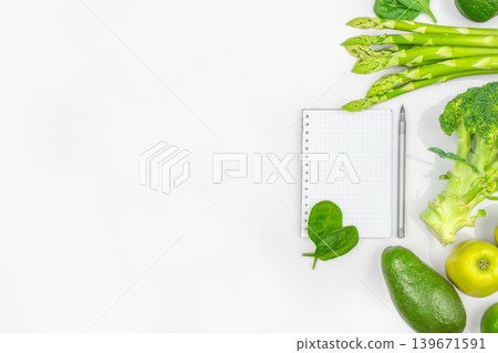 Healthy food border with vegetables notebook and copy space on white background top view Healthy food border with vegetables notebook and copy space on white background top view 139671591