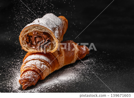 Chocolate filled croissants with powdered sugar on dark background, luxury dessert concept Chocolate filled croissants with powdered sugar on dark background, luxury dessert concept 139671603