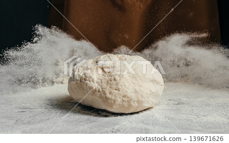 Fresh raw dough with flying flour on dark background for artisan bakery advertising and homemade baking concept 139671626