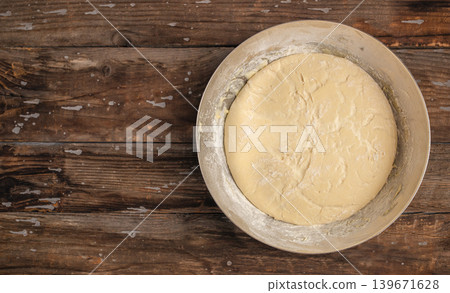 Top view of raw yeast dough in metal bowl on rustic wooden table with copy space for homemade baking concept Top view of raw yeast dough in metal bowl on rustic wooden table with copy space for homemade baking concept 139671628