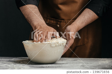 Professional baker kneading sourdough dough in glass bowl for artisan bakery advertising Professional baker kneading sourdough dough in glass bowl for artisan bakery advertising 139671656