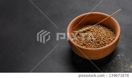 Wheat grains in wooden bowl on dark rustic background with copy space for organic food branding Wheat grains in wooden bowl on dark rustic background with copy space for organic food branding 139671678