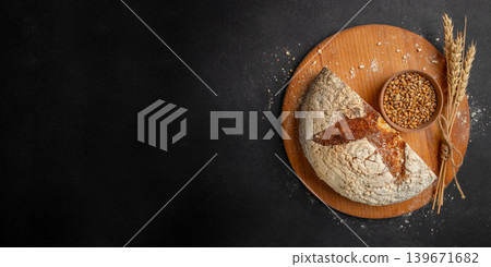 Artisan sourdough bread with wheat grains on dark rustic background top view with copy space Artisan sourdough bread with wheat grains on dark rustic background top view with copy space 139671682