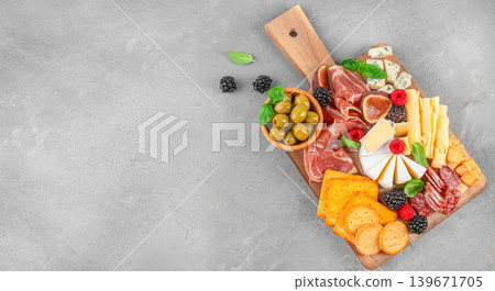 Charcuterie board with cheese prosciutto olives and crackers on gray background with copy space Charcuterie board with cheese prosciutto olives and crackers on gray background with copy space 139671705