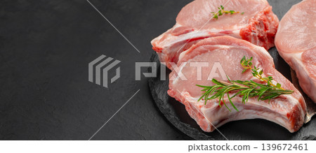 Raw pork chops with herbs on black slate plate over dark background with copy space Raw pork chops with herbs on black slate plate over dark background with copy space 139672461