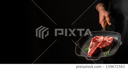 Man holding grill pan with raw porterhouse steak on black background, dramatic lighting. copy space Man holding grill pan with raw porterhouse steak on black background, dramatic lighting. copy space 139672561