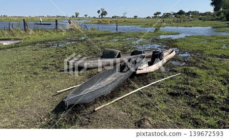 Three canoes lined up on land and a daytime view of a wetland. Three canoes lined up on land and a daytime view of a wetland. 139672593