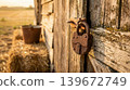 Heavy rusted iron padlock hanging on weathered wooden barn door 139672749