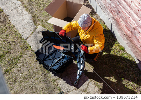 Modular compost system with stackable plastic parts being unpacked by rural resident near country home. 139673214