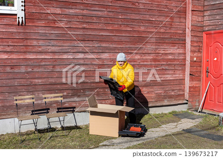 Plastic compost container for self assembly standing beside homeowner removing molded panels from package. Plastic compost container for self assembly standing beside homeowner removing molded panels from package. 139673217