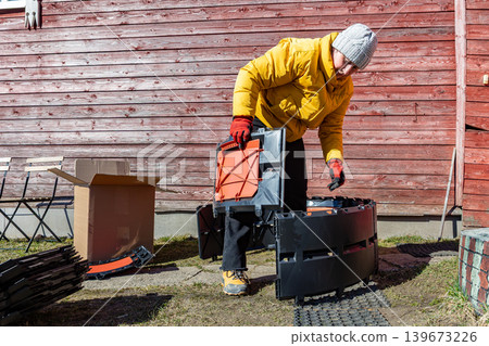 Curved compost container formed from identical plastic modules while female rural resident attaches new section. 139673226