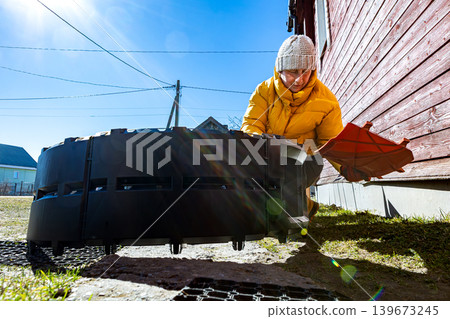 Stackable compost container taking shape while rural woman connects interlocking plastic panels outdoors. Stackable compost container taking shape while rural woman connects interlocking plastic panels outdoors. 139673245