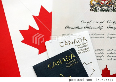 Canadian temporary passport and certificate of citizenship lies on flag 139673345