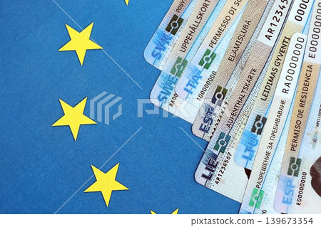 Permanent resident or residence permit cards lies on European Union flag. Paper specimen cards Permanent resident or residence permit cards lies on European Union flag. Paper specimen cards 139673354