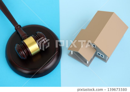Generic toy house and judgement mallet on blue background Generic toy house and judgement mallet on blue background 139673380