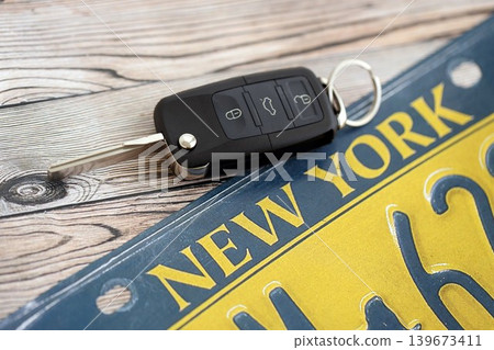 Remote control car keys on New York license plate on wooden background. Car driving in New York Remote control car keys on New York license plate on wooden background. Car driving in New York 139673411