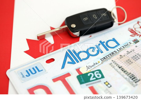 Alberta canadian car license plate and ignition key on flag of Canada close up Alberta canadian car license plate and ignition key on flag of Canada close up 139673420