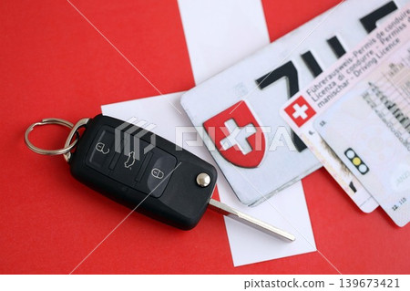 Switzerland car license plate and ignition key on Swiss flag close up. Driving permit 139673421