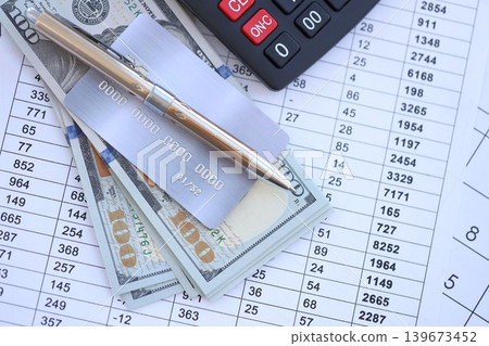 Credit card and pen with US dollar currency money bills banknotes on calculations document Credit card and pen with US dollar currency money bills banknotes on calculations document 139673452