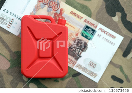 Petrol canister on russian roubles money bills on camouflage fabric. Concept of petroleum export Petrol canister on russian roubles money bills on camouflage fabric. Concept of petroleum export 139673466