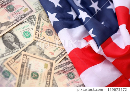 American Flag Draped Over Piles of US Dollar Bills. Symbolizing Wealth and Patriotism in the USA 139673572