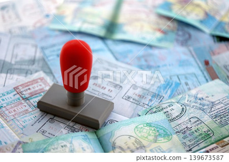 Border crossing stamp on big amount of passport pages full of colorful stamps after travel Border crossing stamp on big amount of passport pages full of colorful stamps after travel 139673587