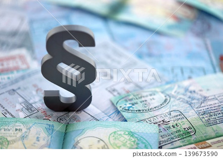 Paragraph symbol on passport pages full of colorful stamps after travel and tourism Paragraph symbol on passport pages full of colorful stamps after travel and tourism 139673590