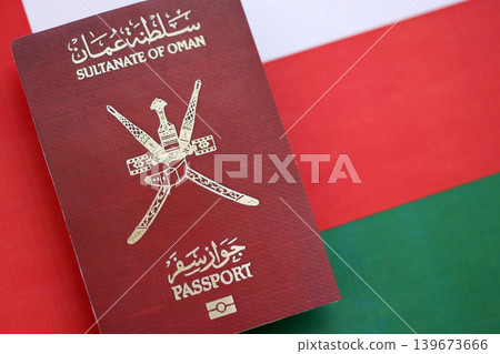 Omani passport on flag close up. Official identification document book for citizens of Oman Omani passport on flag close up. Official identification document book for citizens of Oman 139673666