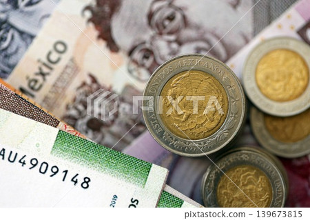 Mexican peso money bills and centavo coins pile on table. Mexico coins on banknotes of MXN currency Mexican peso money bills and centavo coins pile on table. Mexico coins on banknotes of MXN currency 139673815