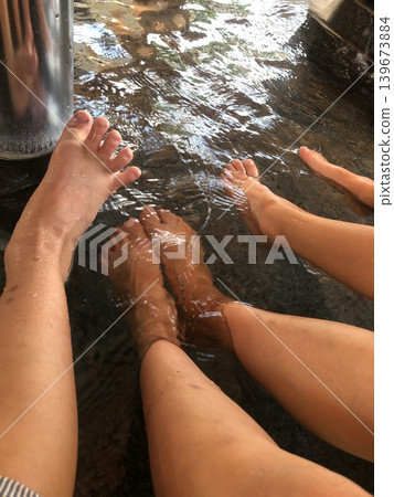 一位女士在足浴盆裡洗手時,她的腳在清洗。 一位女士在足浴盆裡洗手時,她的腳在清洗。 139673884