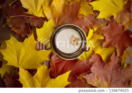 Autumn leaves with a cup of coffee on a wooden surface, cozy seasonal mood, fall relaxation, warm lifestyle, Thanksgiving. 139674035