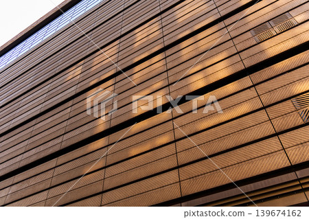 Contemporary architectural facade metal cladding with diagonal lines and sunlight of modern building Contemporary architectural facade metal cladding with diagonal lines and sunlight of modern building 139674162
