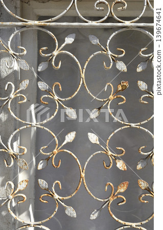 Ornate rusty wrought iron window grill with leaf motifs Ornate rusty wrought iron window grill with leaf motifs 139674641