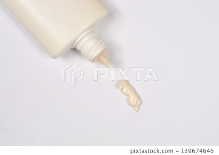 Beige cosmetic cream squeezed from a white plastic tube 139674646