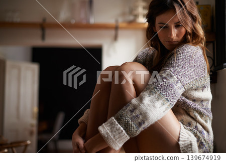 Sad, lonely and young woman at a home with upset, grief and mad facial expression for problem. Mental health, emotion and depressed female person looking down with unhappy face for loss at house. Sad, lonely and young woman at a home with upset, grief and mad facial expression for problem. Mental health, emotion and depressed female person looking down with unhappy face for loss at house. 139674919