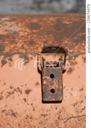 Close up of a rusty metal latch on an orange surface 139674979