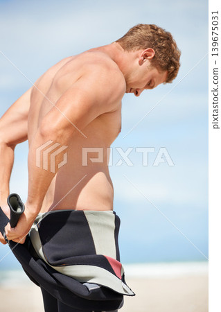 Surfer, man and getting ready with wetsuit on beach with body, blue sky and dressing with fitness or wellness. Rear view, athlete and person by ocean for training, surfing workout and extreme sports Surfer, man and getting ready with wetsuit on beach with body, blue sky and dressing with fitness or wellness. Rear view, athlete and person by ocean for training, surfing workout and extreme sports 139675031