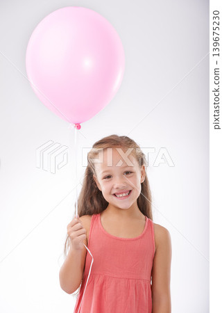 Girl, child and balloon in portrait, party decoration and smiling for milestone event in studio. Happy female person, inflatable accessory and birthday joy on white background, playful and celebrate 139675230