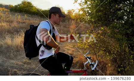 Happy young man ride mountain ski bike along trail on sunny summer day. Beautiful golden sunlight at background. Concept of active lifestyle, adventure spirit and carefree weekend outdoor Happy young man ride mountain ski bike along trail on sunny summer day. Beautiful golden sunlight at background. Concept of active lifestyle, adventure spirit and carefree weekend outdoor 139676280