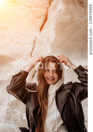 Woman leather jacket young female posing outdoors against white rocky cliffs during golden hour in casual autumn outfit Woman leather jacket young female posing outdoors against white rocky cliffs during golden hour in casual autumn outfit 139676968