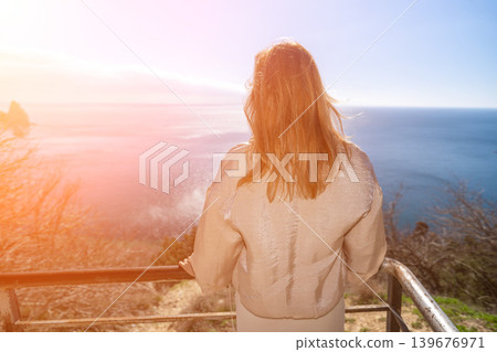 Woman ocean viewpoint woman stands at a scenic lookout overlooking the vast sea under bright sunlight during a peaceful morning Woman ocean viewpoint woman stands at a scenic lookout overlooking the vast sea under bright sunlight during a peaceful morning 139676971