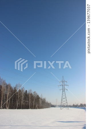 High voltage power line tower over snowy winter landscape High voltage power line tower over snowy winter landscape 139677037