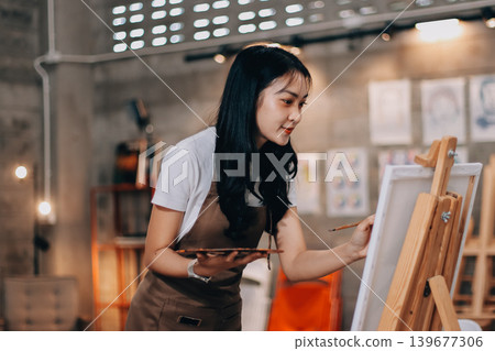 Female artist wears black hat posing near picture indoor the studio Female artist wears black hat posing near picture indoor the studio 139677306