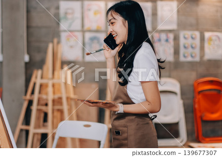 Female artist wears black hat posing near picture indoor the studio Female artist wears black hat posing near picture indoor the studio 139677307
