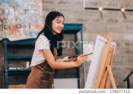 Female artist wears black hat posing near picture indoor the studio 139677318