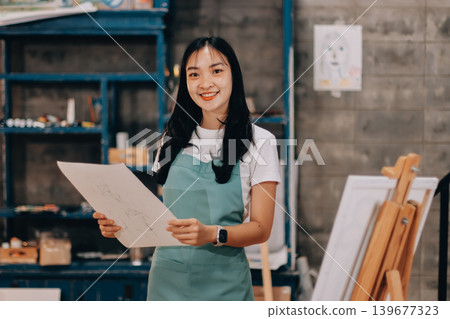 Female artist wears black hat posing near picture indoor the studio Female artist wears black hat posing near picture indoor the studio 139677323