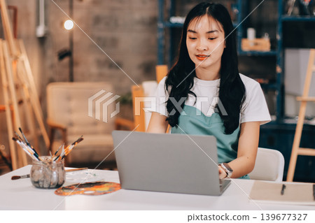 Female artist wears black hat posing near picture indoor the studio Female artist wears black hat posing near picture indoor the studio 139677327